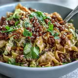 Colorful Potsticker Noodle Bowls topped with browned pork, shredded carrots, green cabbage, and sesame seeds.