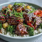 Steaming Teriyaki Chicken and Rice Bowl topped with juicy pineapple chunks, scallions, and toasted sesame seeds ready for dinner.