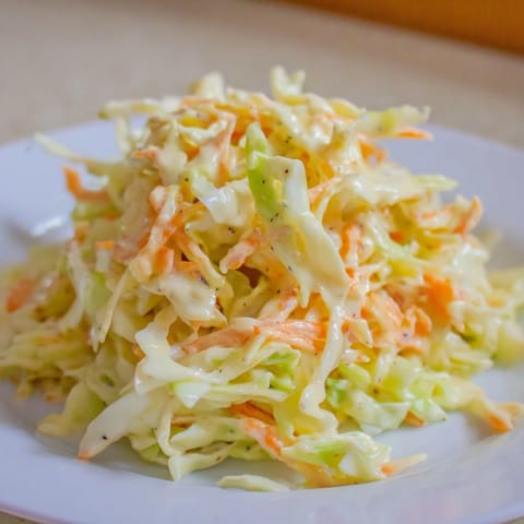Freshly prepared Coleslaw served chilled from a white bowl, a crunchy side for barbecue plates.