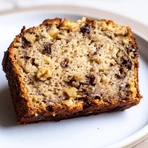 A thick slice of moist banana bread topped with melting butter, paired with a hot cup of coffee.
