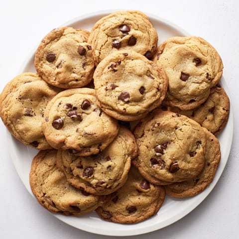 Freshly baked Chocolate Chip Cookies with gooey centers served alongside a cold glass of milk.