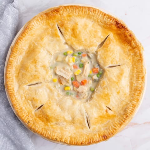 Freshly baked Chicken Pot Pie sits beside a green salad, ready for a comforting family dinner.