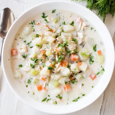 Bowl of rich Clam Chowder garnished with fresh parsley, ready to enjoy with crusty bread.