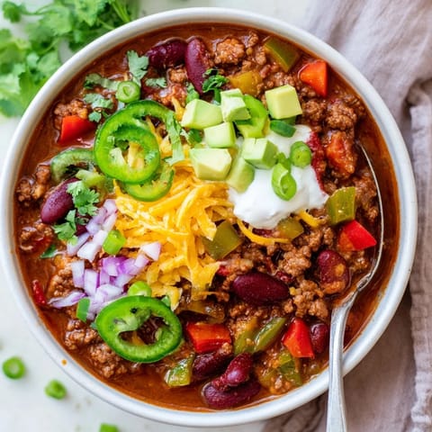 Hearty chili con carne simmering in a pot with red kidney beans, diced tomatoes, and fresh cilantro.