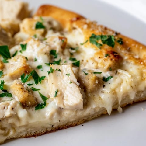 Golden-brown Chicken Alfredo Pizza with creamy Alfredo sauce, tender chicken, and melted mozzarella on a rustic crust.