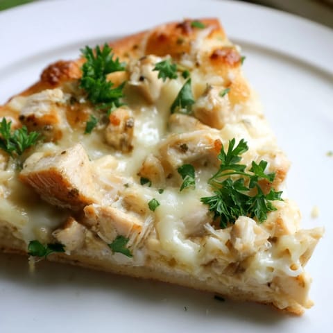 Sliced Chicken Alfredo Pizza shows bubbling cheeses and golden chicken on a creamy Alfredo sauce base.