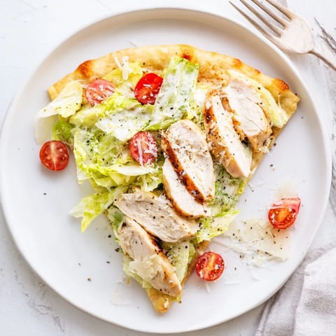 Golden-brown Caesar Chicken Flatbread topped with juicy grilled chicken, crisp romaine, and creamy Caesar dressing on a white plate.  