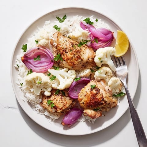 A close-up of the Roasted Cauliflower Chicken Sheet Pan, highlighting tender florets and juicy chicken with a smoky paprika glaze.  