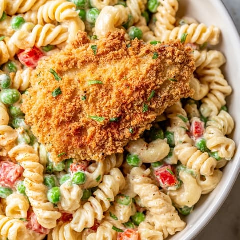Tender pasta and golden crispy chicken bites tossed with sweet peas in a creamy ranch dressing, served chilled.