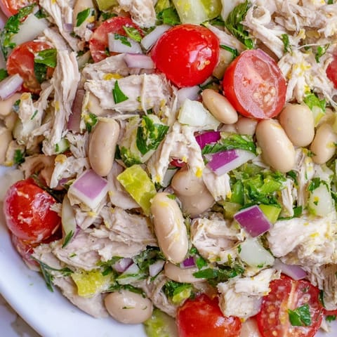 A bright bowl of Lemony White Bean Chicken Salad with fresh dill, parsley, and juicy cherry tomatoes ready for a summery lunch.