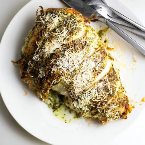 Sliced Mozzarella & Pesto Stuffed Chicken served alongside roasted vegetables and a glass of white wine on a rustic table.  