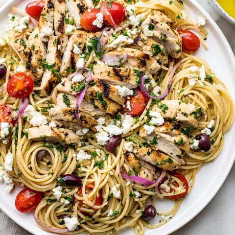 Steaming Greek Chicken Spaghetti features juicy grilled chicken, briny Kalamata olives, and crumbled feta over al dente pasta.