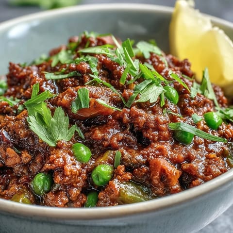 Close-up of aromatic Venison Keema Curry featuring tender ground venison and vibrant peas in a rich sauce.