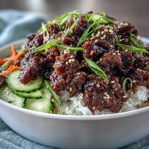 Heaping serving of an Easy Korean Beef Bowl with colorful carrots and green onions on fluffy cauliflower rice.