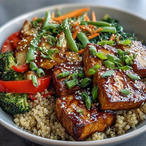 Crispy tofu cubes and vibrant stir-fried vegetables on fluffy quinoa, drizzled with savory teriyaki sauce in a beautiful bowl.