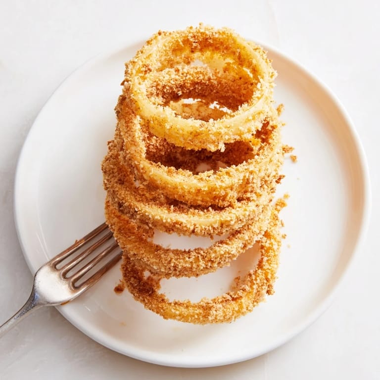 Homemade onion rings, perfectly deep-fried until crunchy and golden, paired with ketchup for an irresistible American appetizer snack.