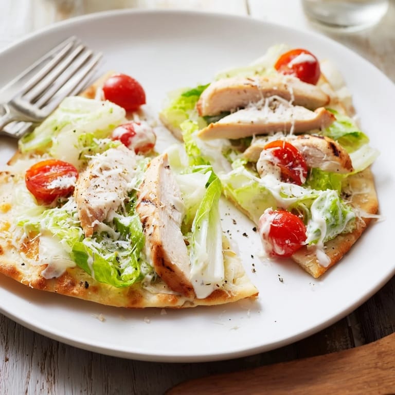Sliced Caesar Chicken Flatbread with fresh romaine, cherry tomatoes, and grated Parmesan garnished with lemon wedges.  
