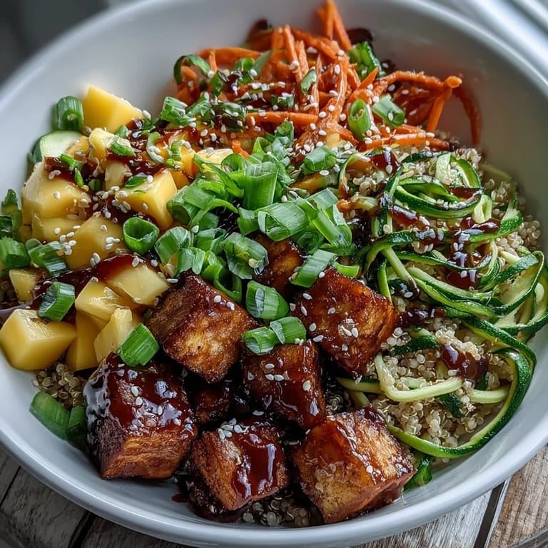 A close-up view of Easy Teriyaki Quinoa Bowl features gluten-free teriyaki sauce drizzled over baked tofu, fresh spiralized veggies, and fluffy quinoa.