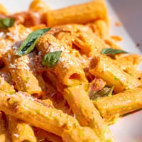 Creamy Roasted Red Pepper Pasta in a white bowl, garnished with fresh basil and extra Parmesan cheese for a weeknight vegetarian dinner.