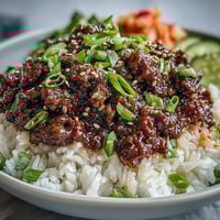 Vibrant Korean Beef Bowl with spicy gochujang glazed beef over fluffy white rice, topped with pickled daikon, crisp cucumber slices, and chopped kimchi.